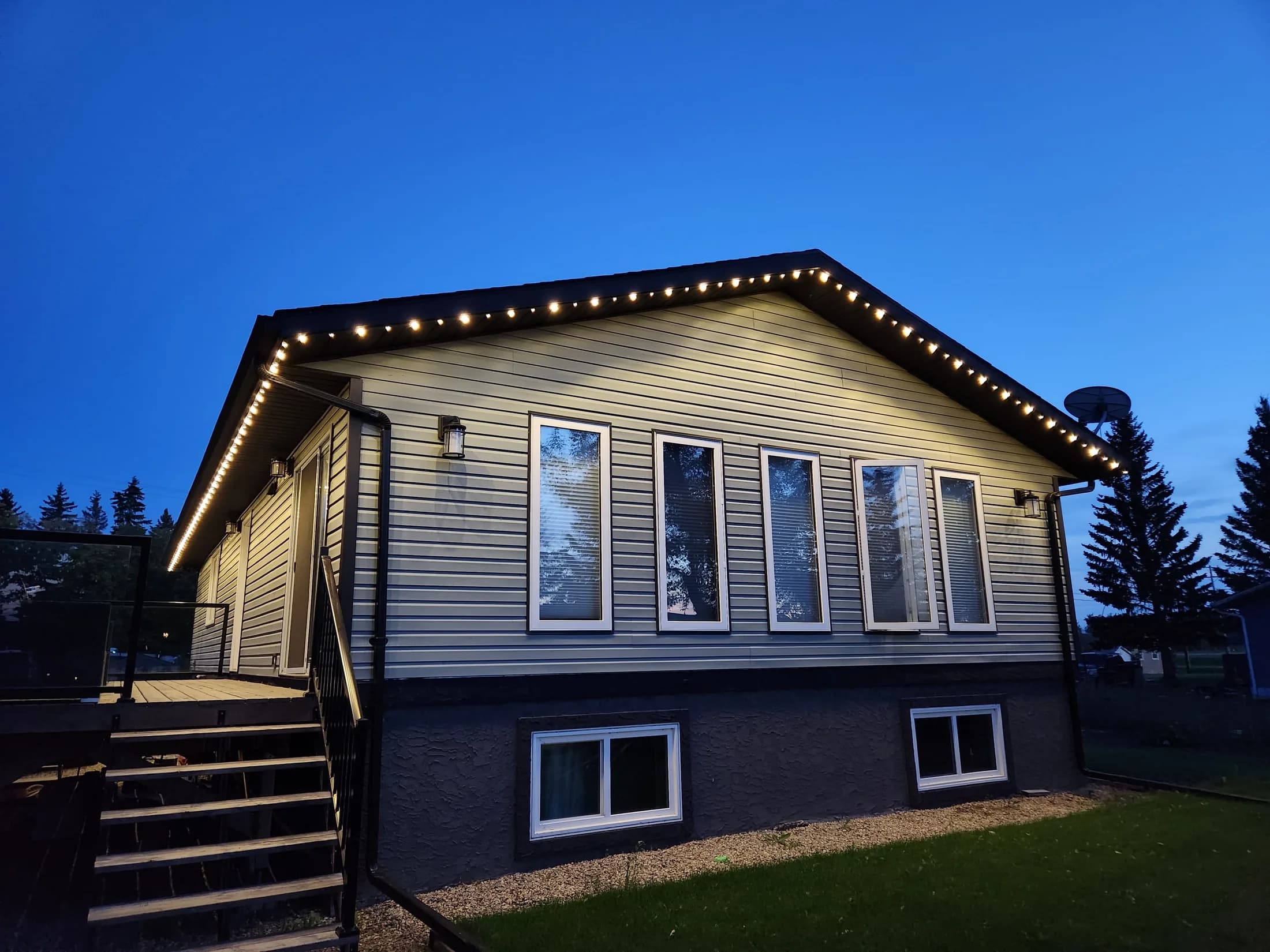 Two-storey home at twilight outlined in warm-white permanent LED track lighting along the roofline