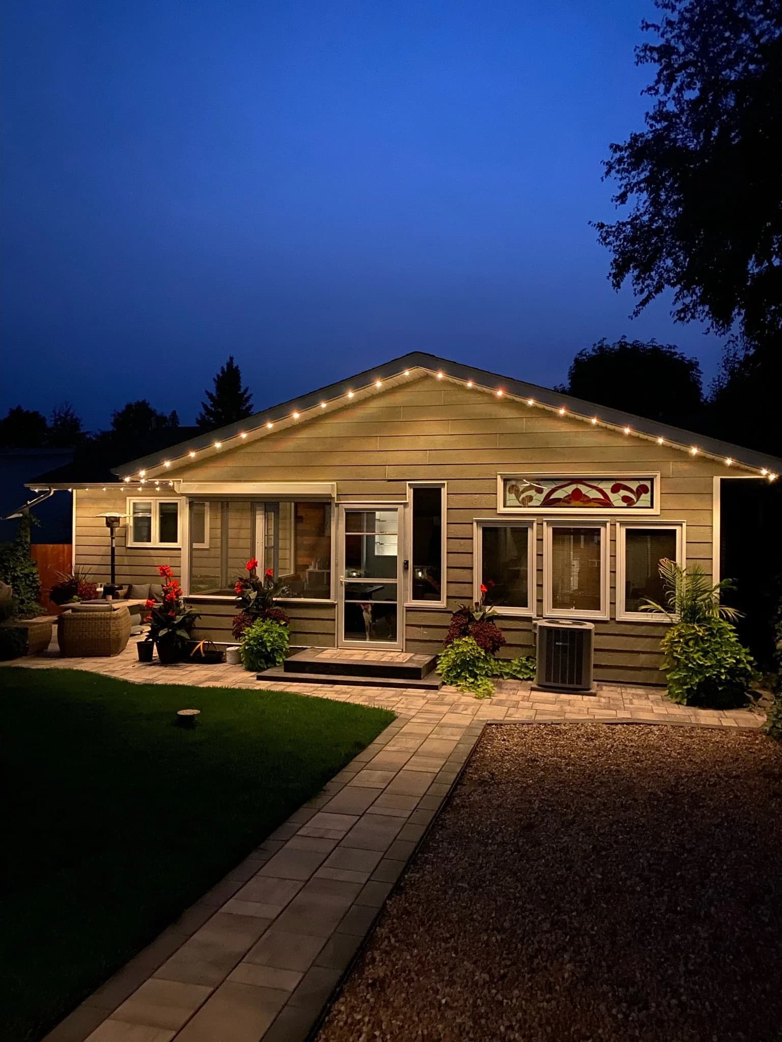 Cottage lit in the evening with warm permanent LED lighting along the eaves