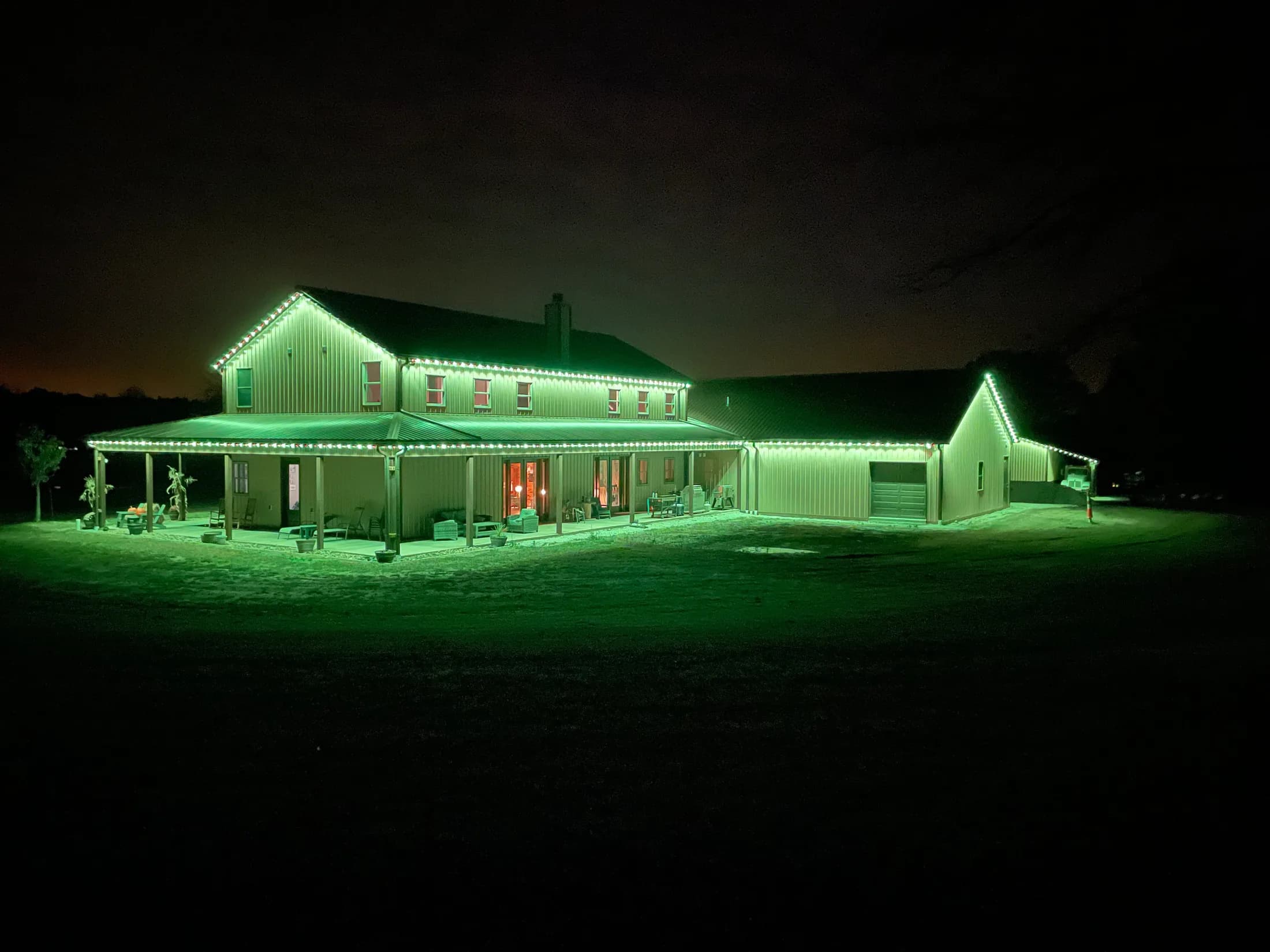 Aluminum-tracked LED lights glowing green along a home's soffit and rooflines at night