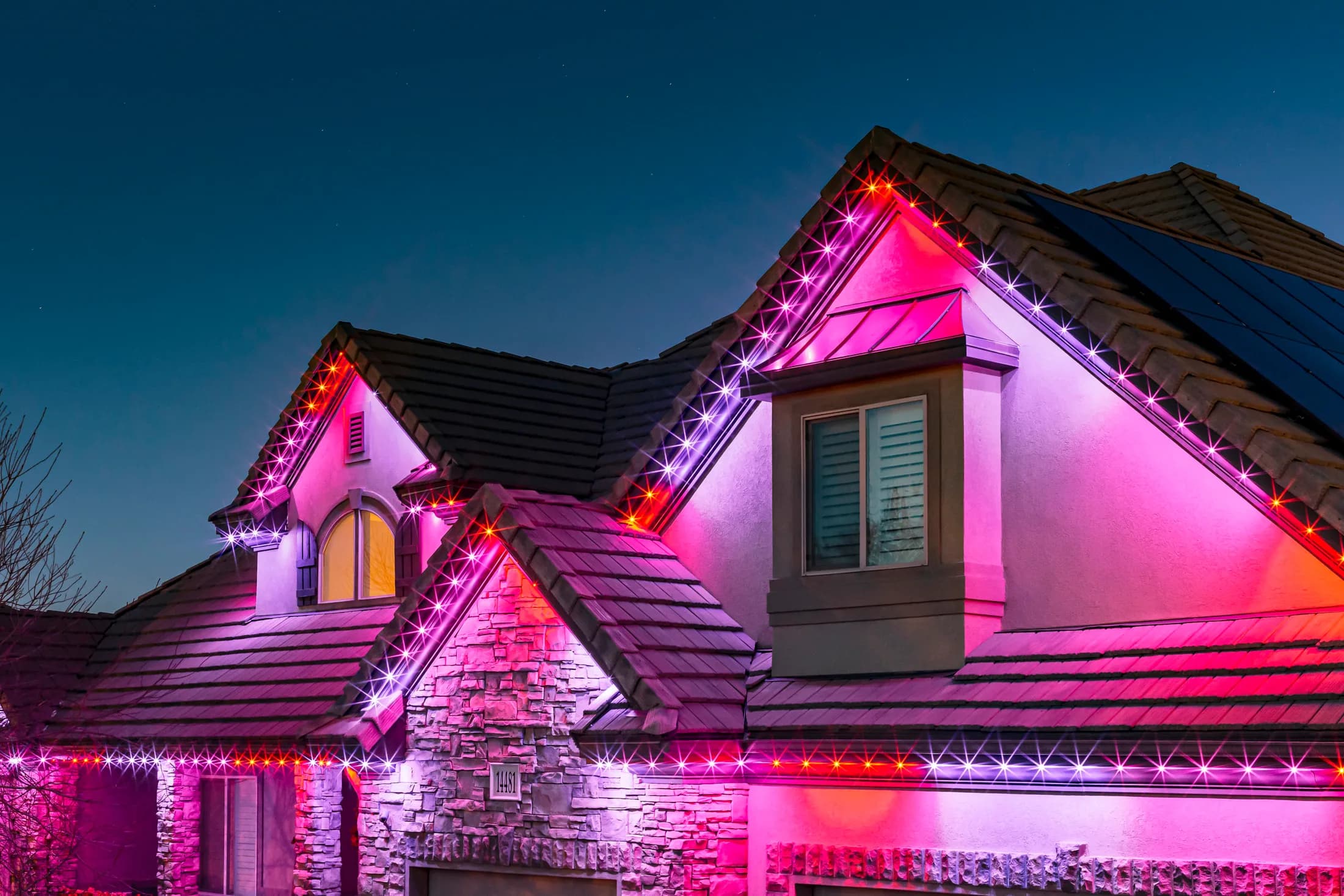 Home exterior lit with warm permanent LED lighting along the roofline and garage