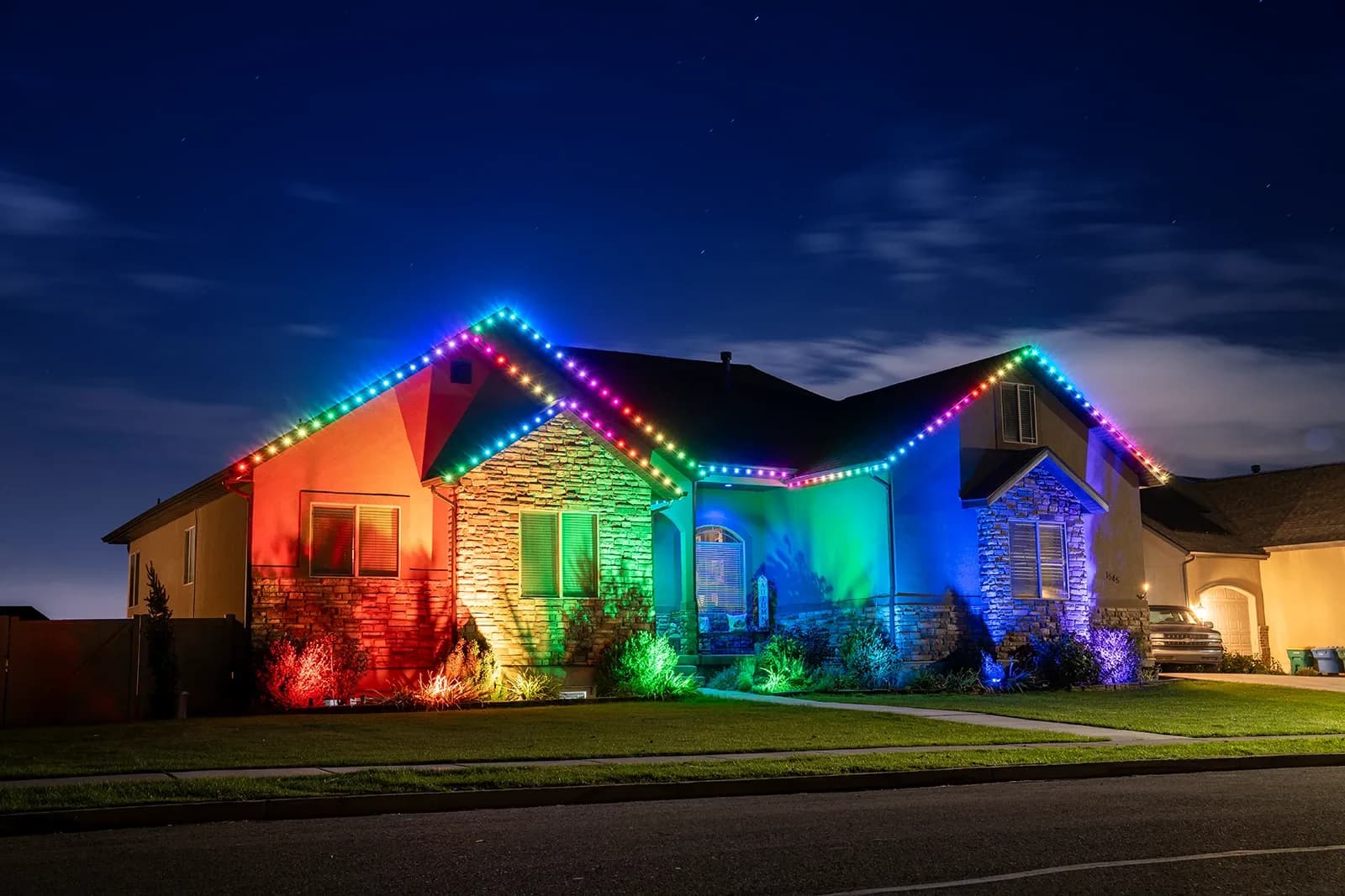 The same roofline at night glowing with warm-white permanent LED lights