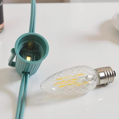 Warm white faceted C9 bulb beside a green E17 socket