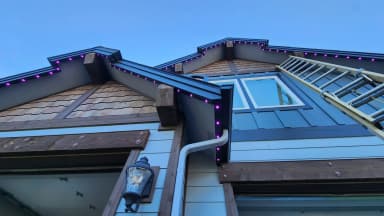 Permanent LED lights in purple along the rooflines of a craftsman-style home