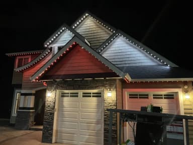 Permanent LED lights in red and white on a home's gables at night