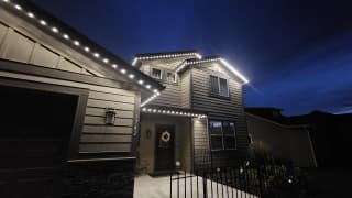Warm white permanent LED roofline lights installed on a two-storey home at night