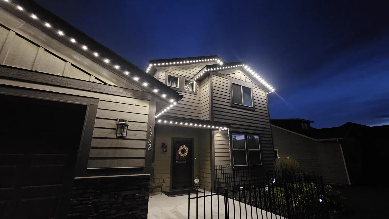 Warm white permanent LED roofline lights installed on a two-storey home at night